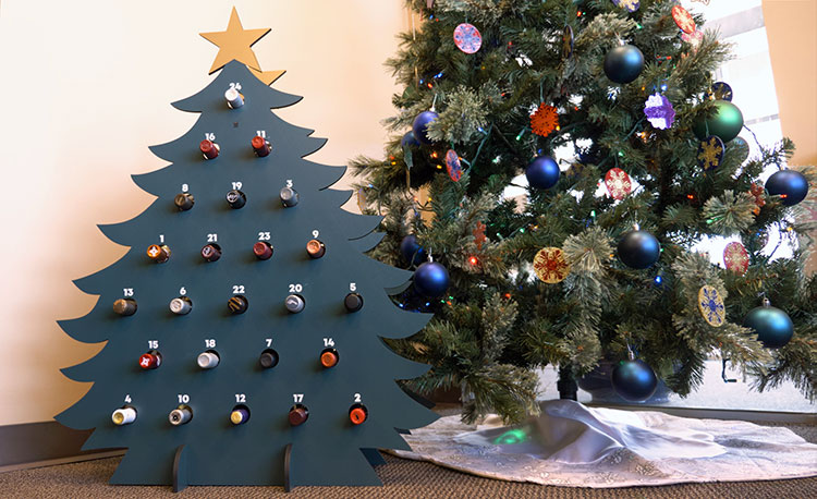 A garrafeira em forma de árvore de natal do advento cortada a laser concluída com garrafas de vinho.