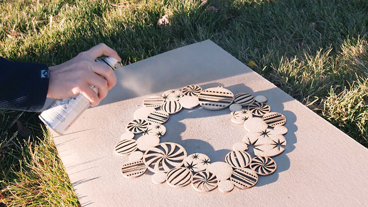 Spray painting a laser cut Christmas wreath.