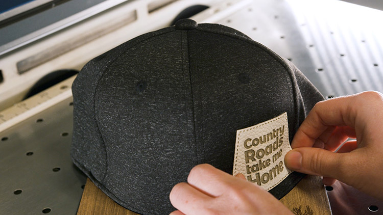 Applying the adhesive leather hat patch to the front of the cap.