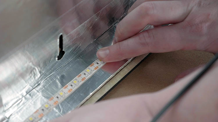 Applying adhesive LED light strip to the interior sides of the box.