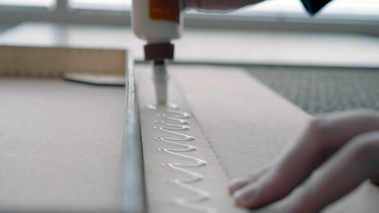 Applying glue to a laser cut piece of plywood.