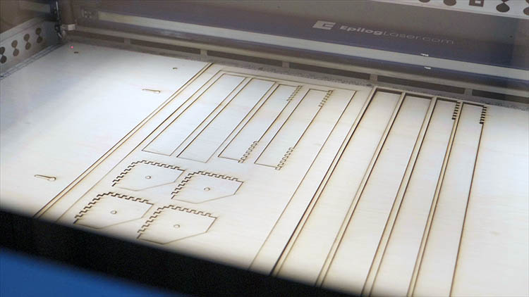 Un foglio di compensato tagliato al laser in un macchinario Epilog Laser.