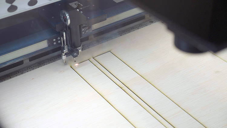 The Epilog Laser cutting out pieces of plywood.