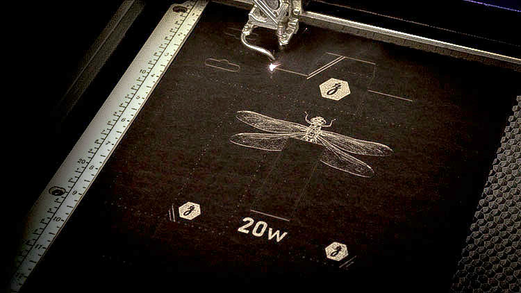 Cardstock being engraved inside an Epilog Laser Helix machine.