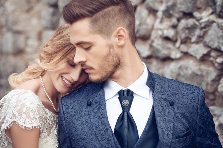 Wedding couple standing against a neutral background.