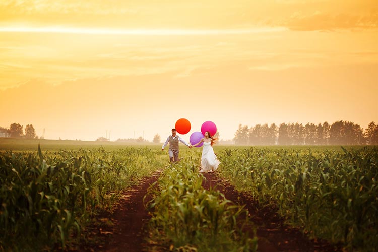 Wedding couple running through a field.