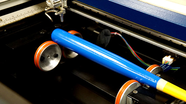 O mini bâtă de baseball plasată pe un dispozitiv rotativ în sistemul laser